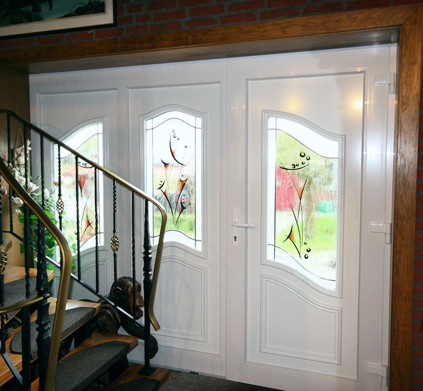 Eine Treppe, die zu einer weißen Tür mit Buntglasfenstern führt