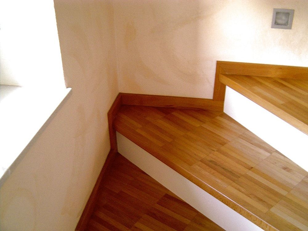 Eine Holztreppe mit einem Lichtschalter an der Wand