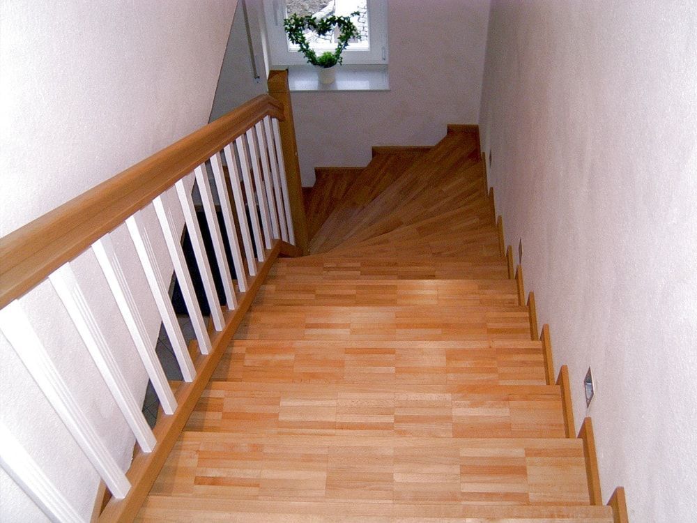 Eine Holztreppe mit weißem Geländer und einem Fenster