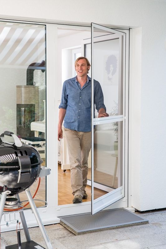 Ein Mann steht in einem Hauseingang neben einem Grill.