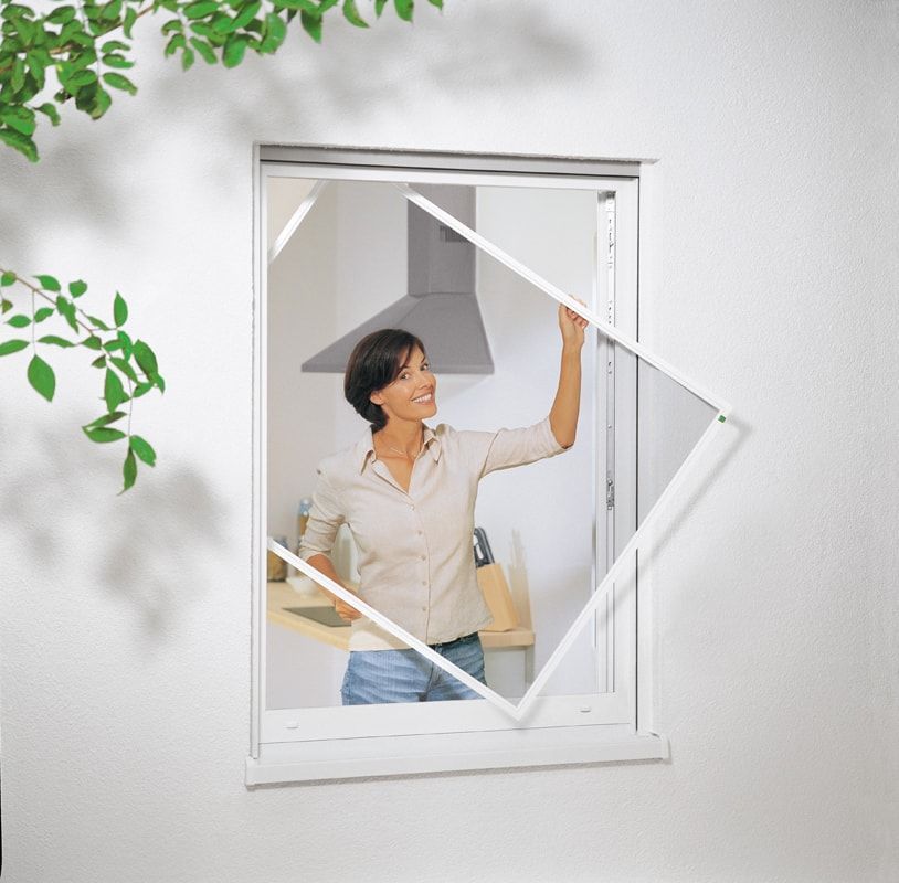 Eine Frau schaut aus einem Fenster mit Fliegengitter