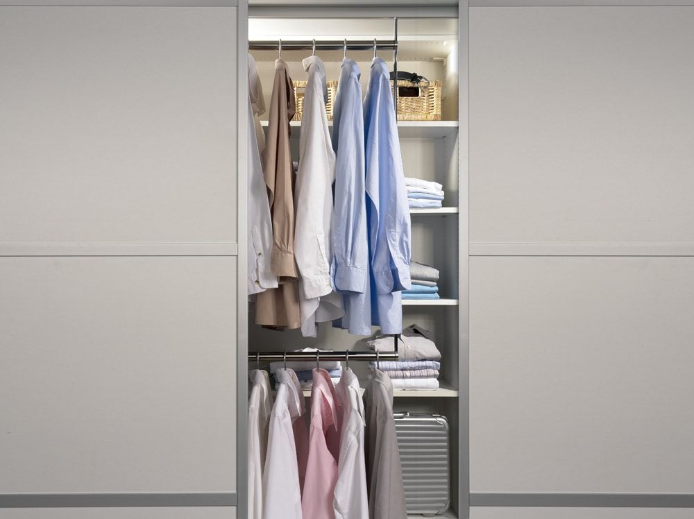 Ein Schiebetürenschrank voller Kleidung und Regalen.