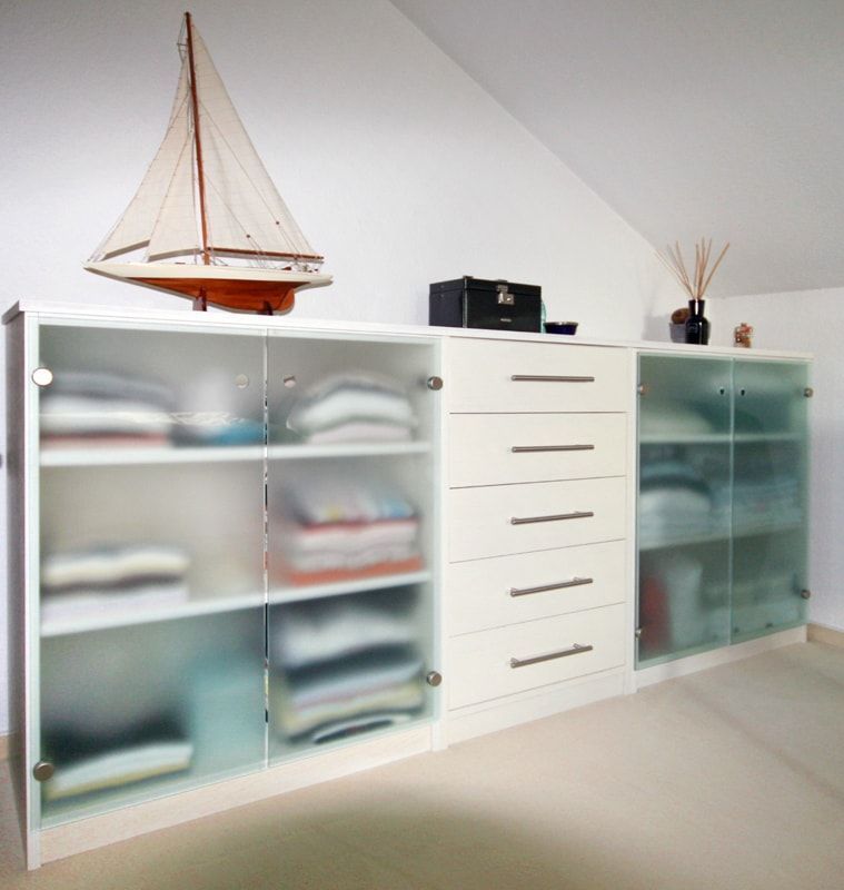 Ein Modellsegelboot steht auf einer Kommode voller Kleidung