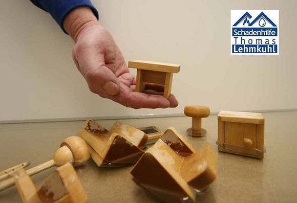 Zwei Arbeiter in einer Werkstatt beim Holzsägen an einer Tischkreissäge, einer von ihnen trägt Gehörschutz und zeigt den Daumen nach oben.