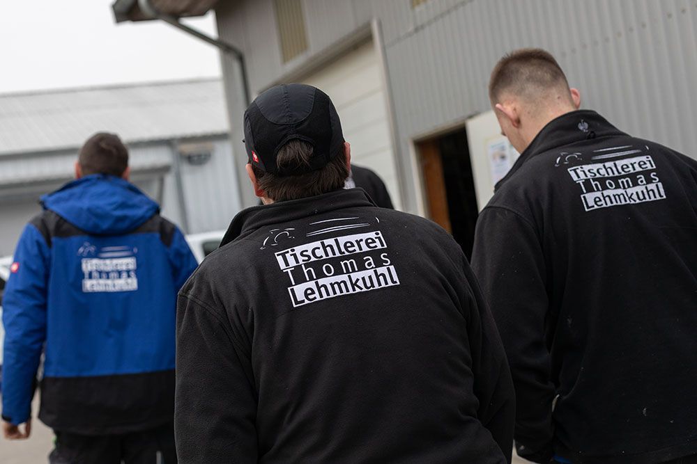 Eine Gruppe von Männern, die schwarze Jacken mit einem Logo auf dem Rücken tragen.