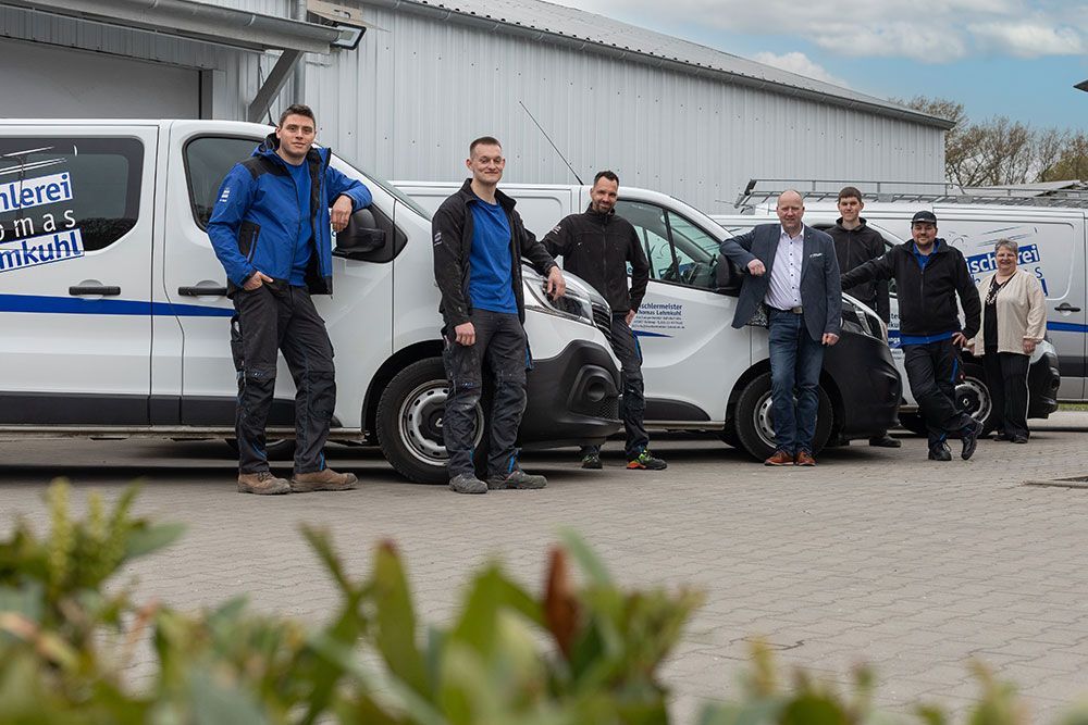 Eine Gruppe Männer posiert vor ihren Lieferwagen für ein Foto.