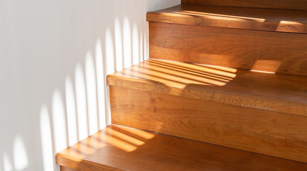 Eine Nahaufnahme einer Holztreppe, auf die die Sonne scheint.
