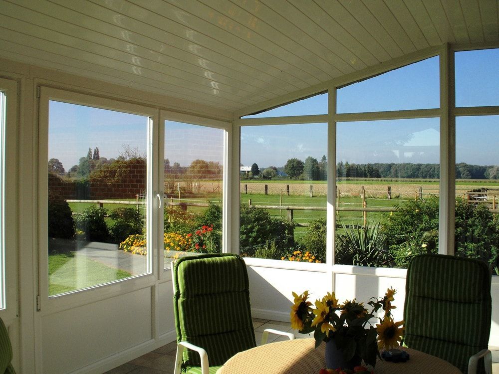 Ein Zimmer mit Tisch und Stühlen und Blick auf ein Feld