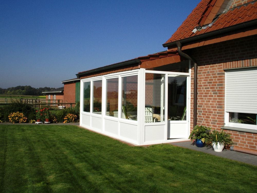 Ein Backsteinhaus mit einer weißen Veranda davor