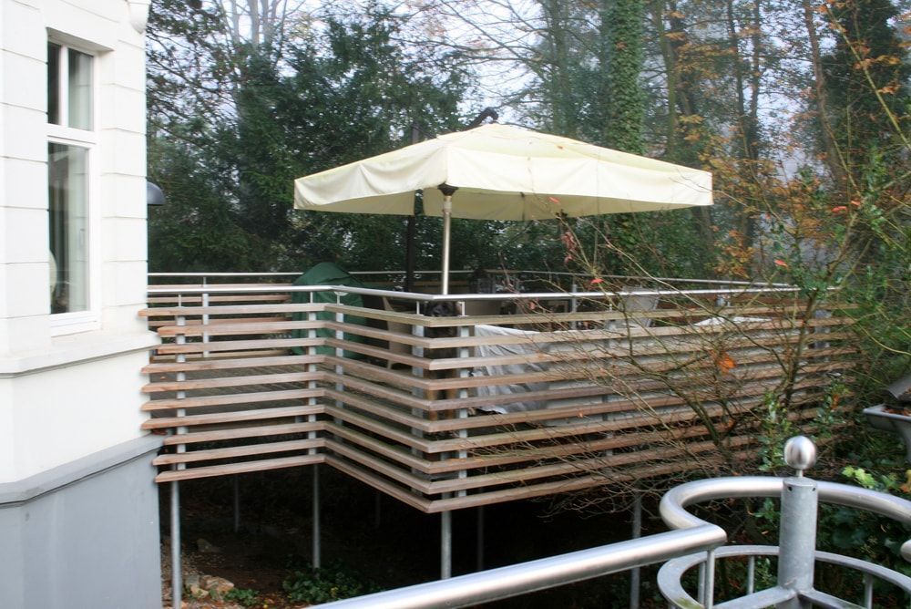 Ein Holzdeck mit einem weißen Sonnenschirm darauf