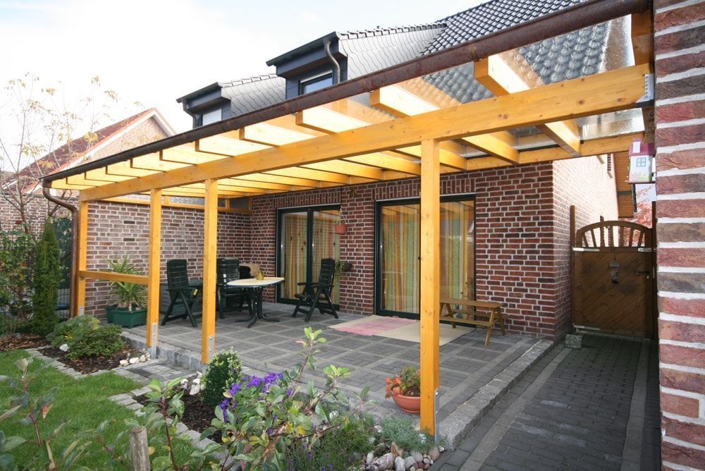 Ein Backsteinhaus mit einer hölzernen Pergola darüber