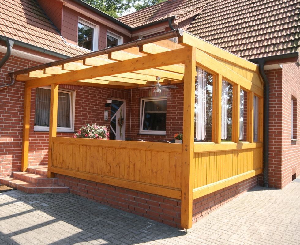 Ein Backsteinhaus mit einer Holzveranda und Treppe