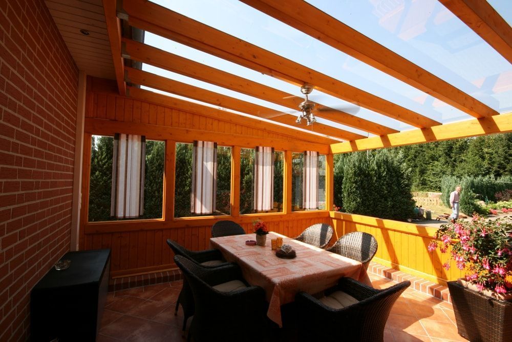 Eine Terrasse mit Tisch und Stühlen unter einem Holzdach