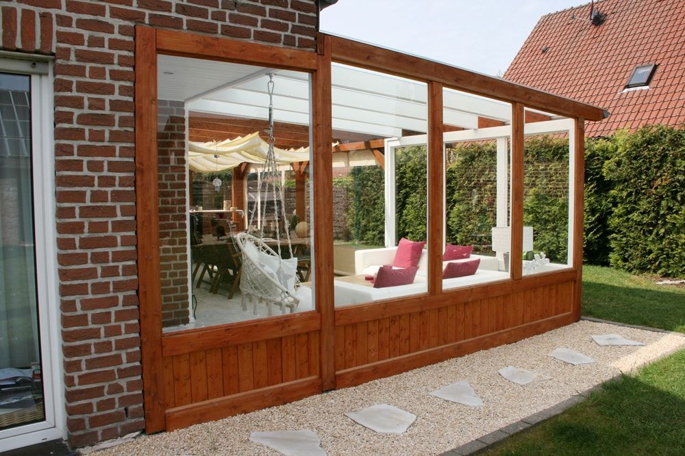 Ein Backsteinhaus mit einer Holzveranda mit vielen Fenstern