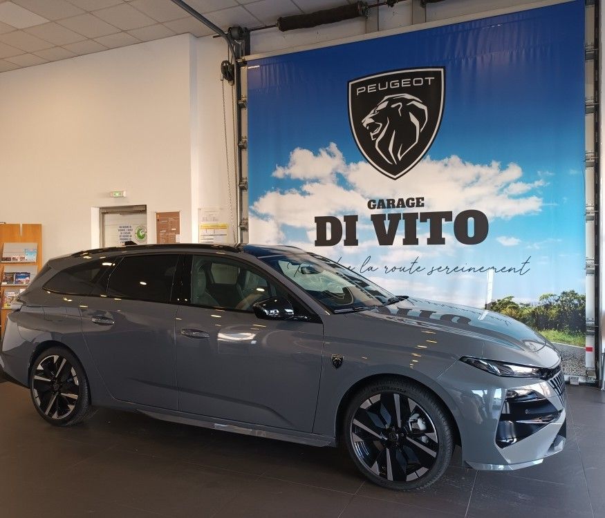 Break Peugeot gris devant une concession automobile avec le logo Peugeot au mur.