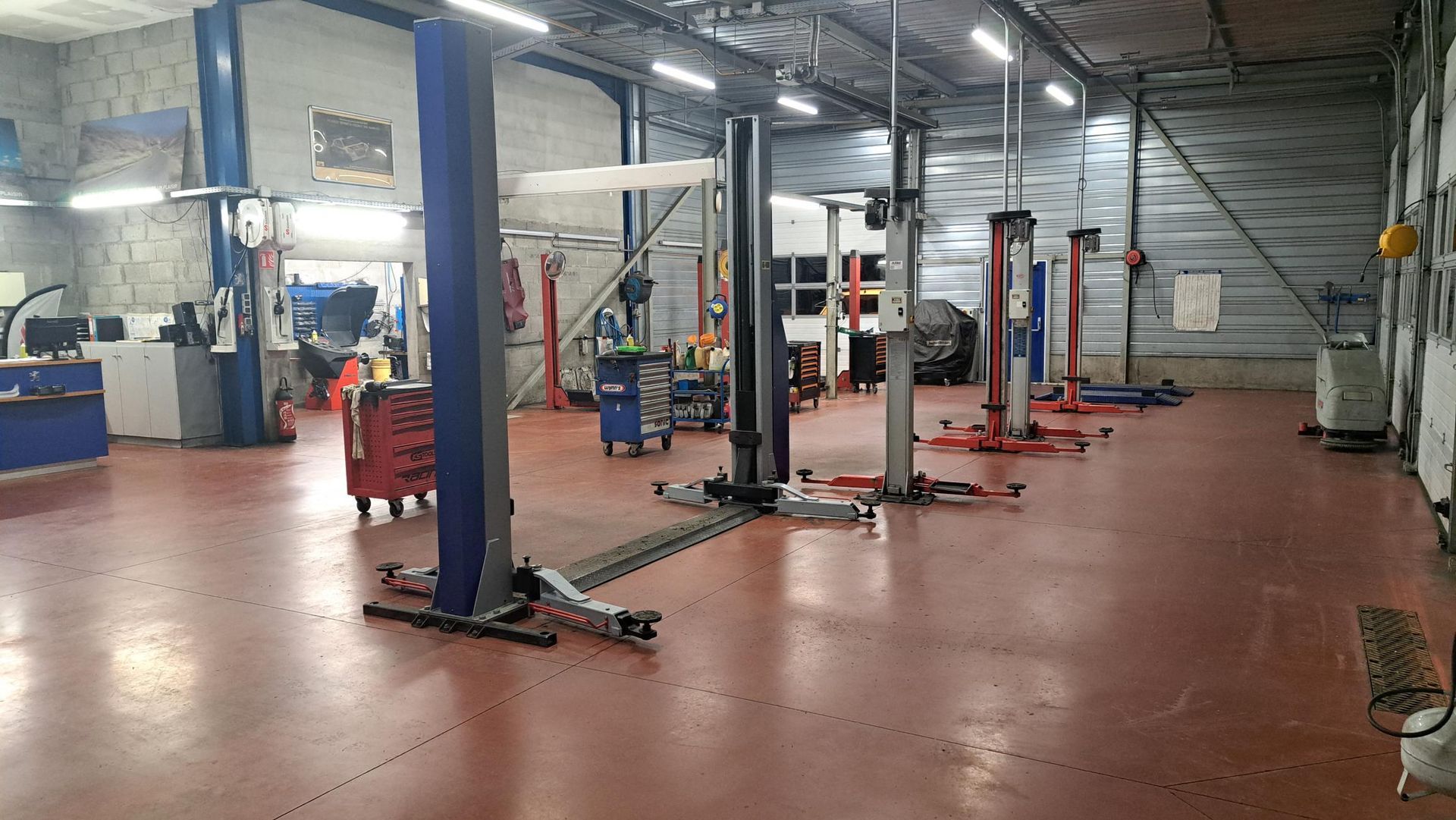 Intérieur d'un atelier de réparation automobile avec plusieurs ponts élévateurs.