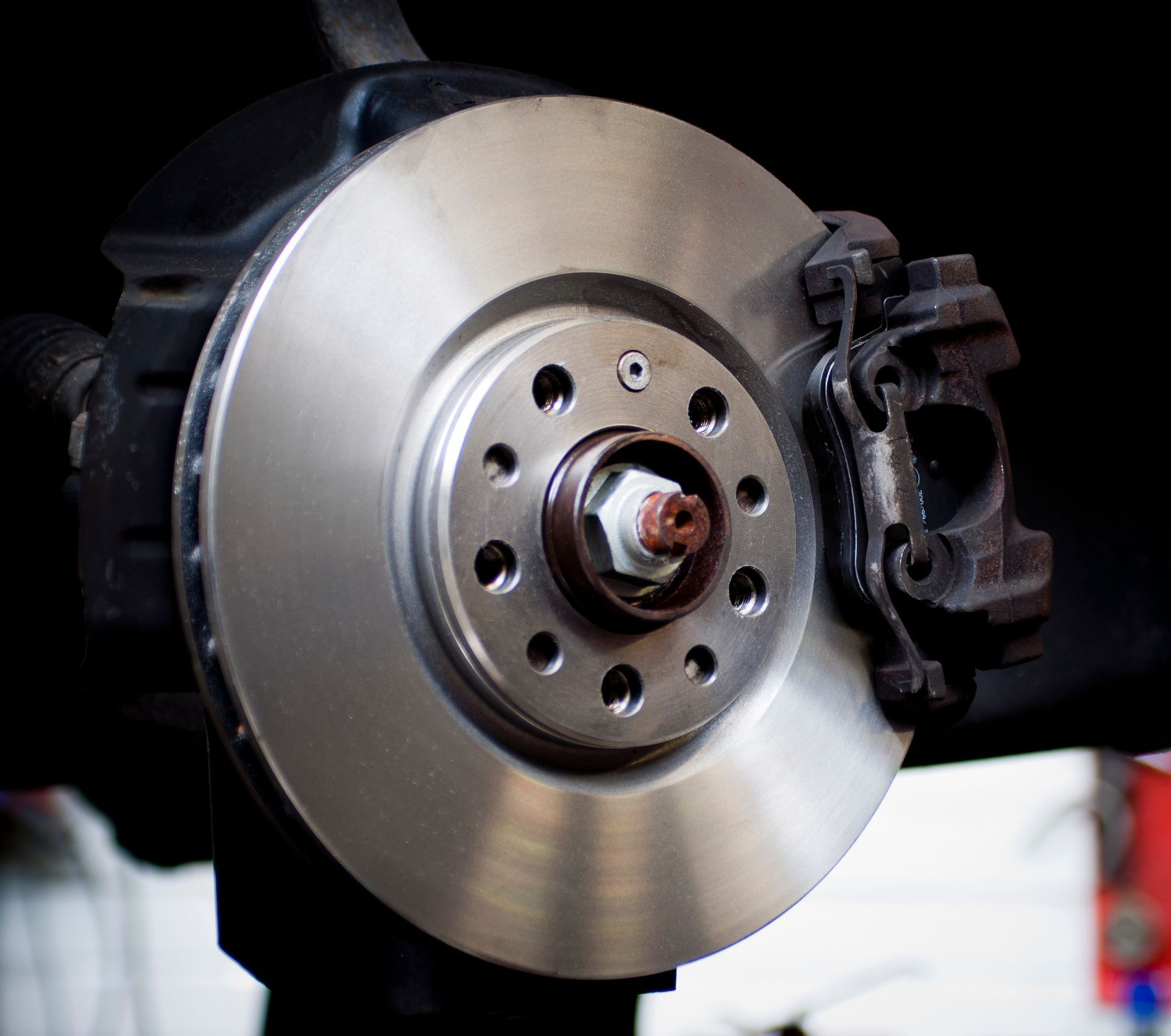 Disque de frein de voiture avec étrier, centré sur un fond noir.