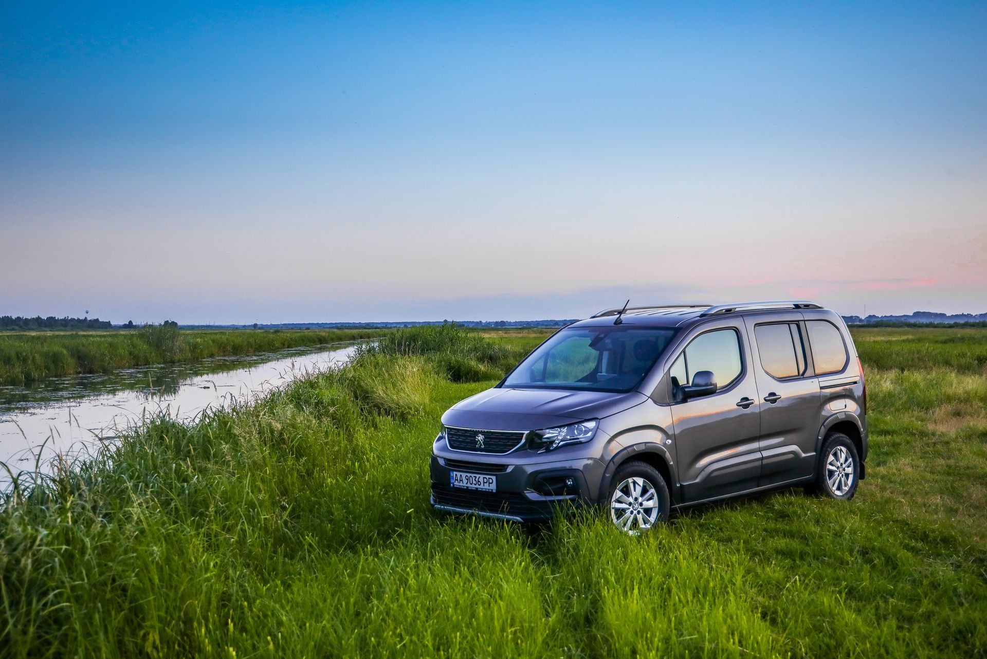 Voiture rouge sur une route sinueuse à travers une forêt, sous un soleil radieux.