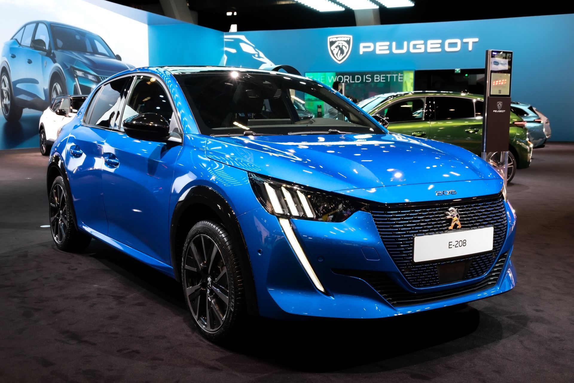 Une Peugeot 208 bleue est exposée lors d'un salon automobile.