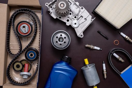 Pièces automobiles : kit de courroie de distribution, pompe à eau, filtre à air, bougies d'allumage, filtre à carburant, filtre à huile et huile sur une table.