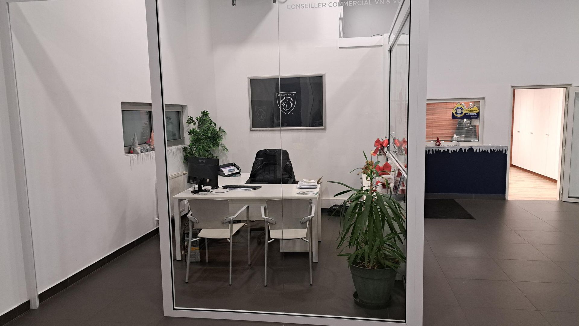 Bureau aux parois vitrées. Bureau avec ordinateur, plantes et chaises.