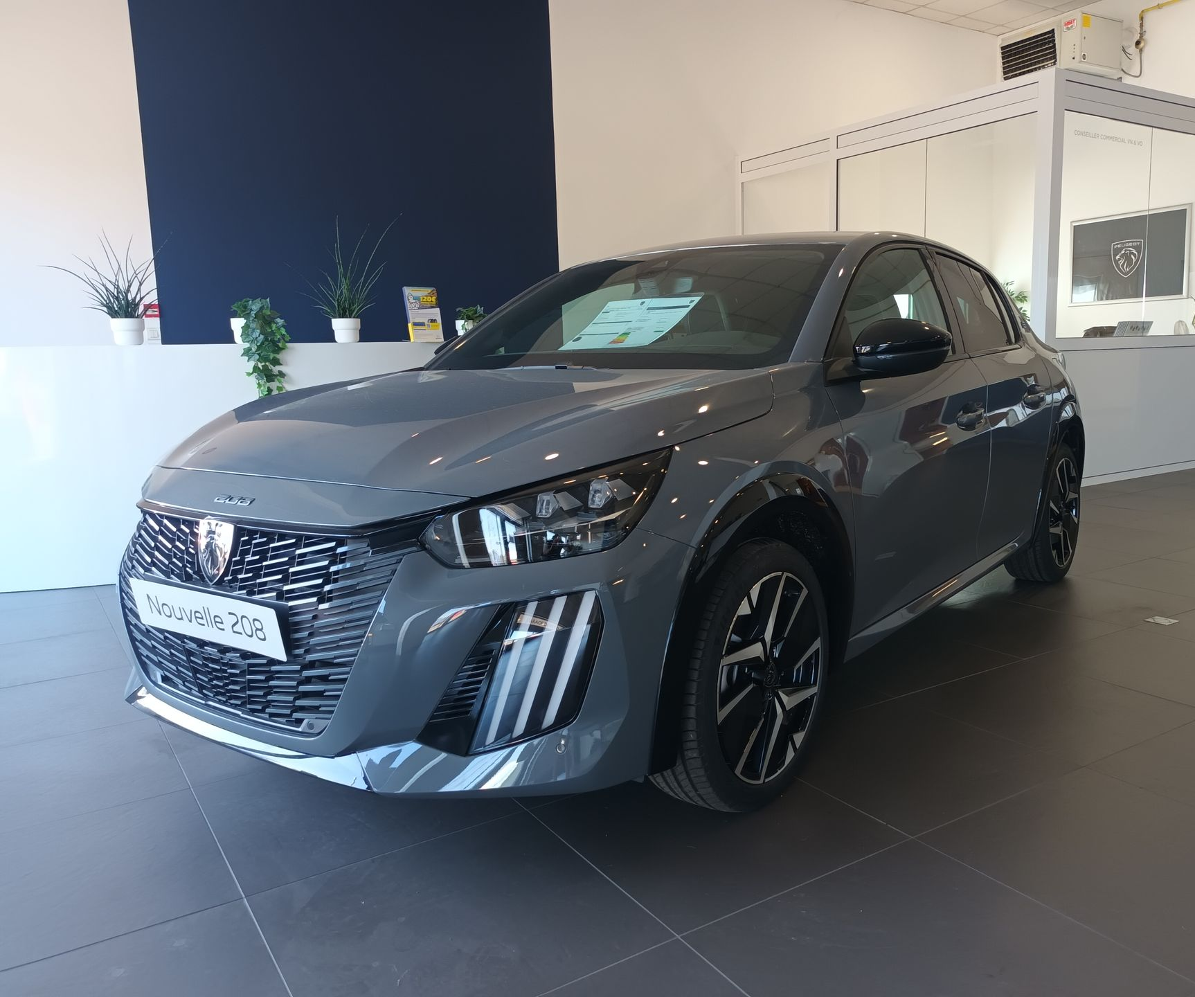 Un SUV Peugeot 208 gris dans une salle d'exposition, avec un intérieur blanc et bleu.
