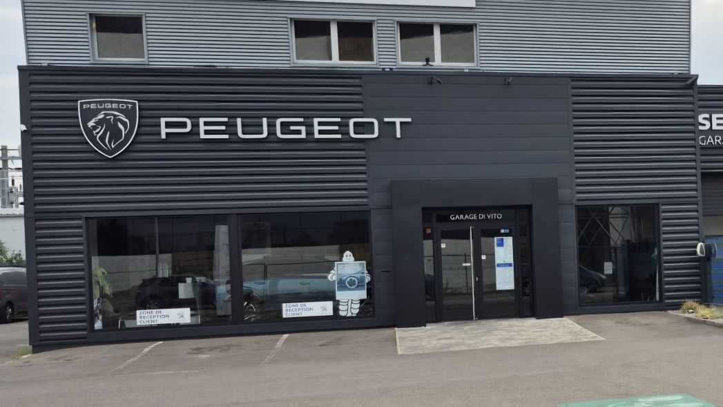 Concessionnaire Peugeot bleu avec une voiture bleue garée devant.