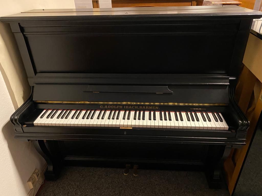 Ein schwarzes Klavier mit weißen Tasten steht auf einem Teppichboden