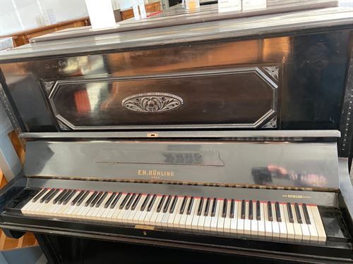 Ein antikes Klavier steht auf einem Holzboden in einem Raum.