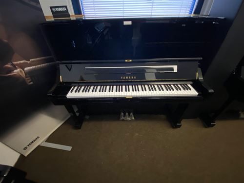 Ein schwarzes Yamaha-Klavier steht vor einem Fenster