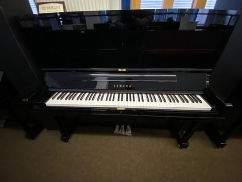 Ein schwarzes Yamaha-Klavier steht auf einem Teppichboden