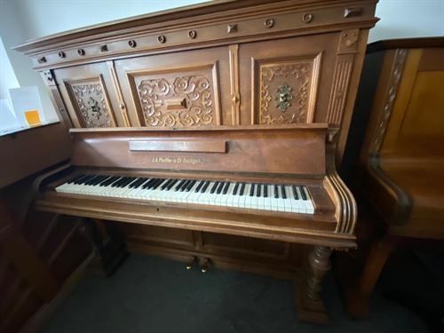 Ein hölzernes Klavier steht in einem Raum mit anderen Klavieren.