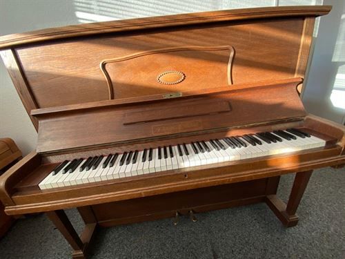 Ein Klavier steht in einem Wohnzimmer neben einem Fenster.