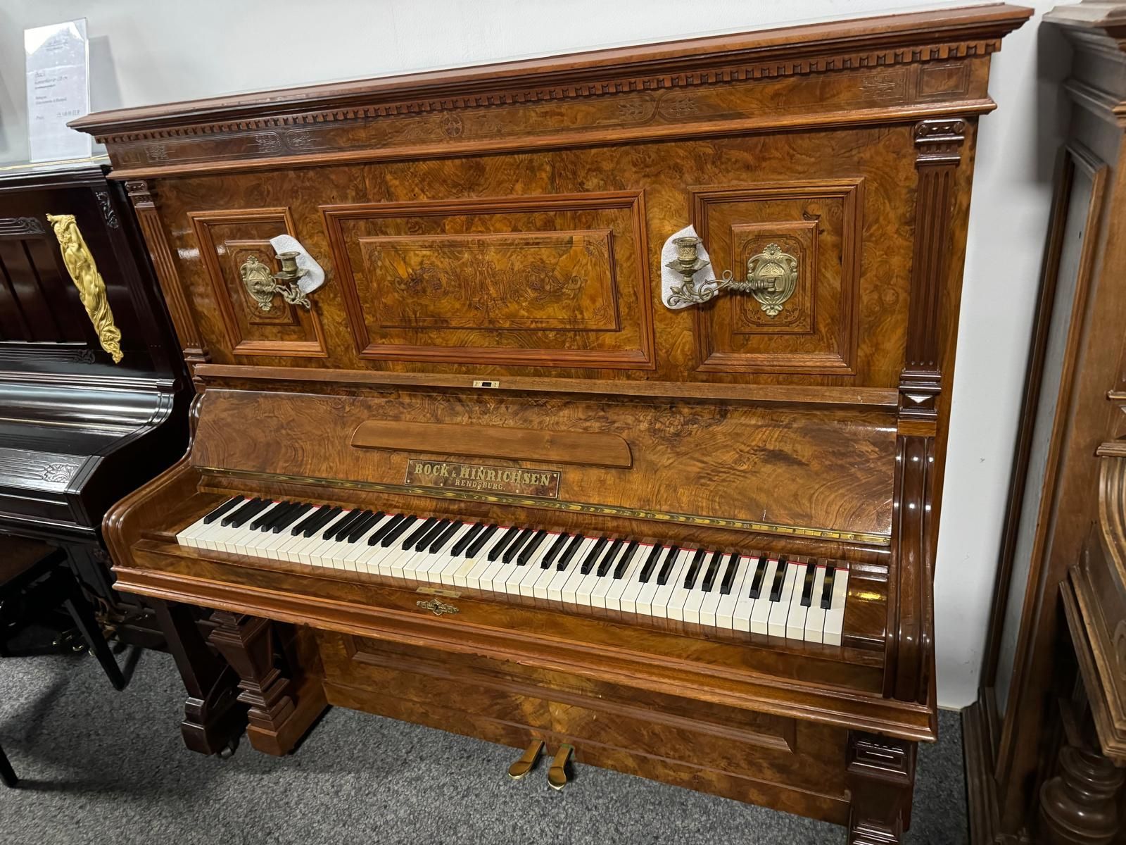 Ein hölzernes Klavier steht in einem Raum mit anderen Klavieren.