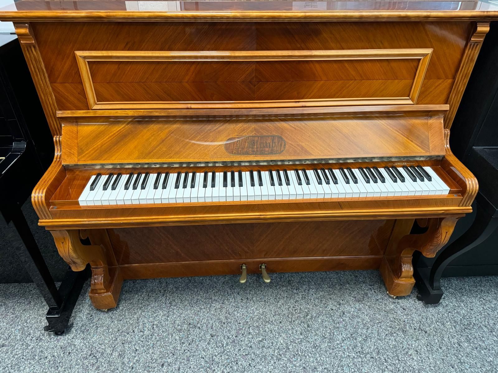 Ein hölzernes Klavier steht in einem Raum mit anderen Klavieren.