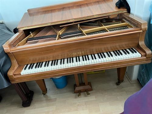 In einem Raum steht ein Klavier auf einem Holzboden.