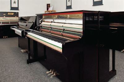 Ein Klavier steht in einem Raum mit anderen Klavieren.