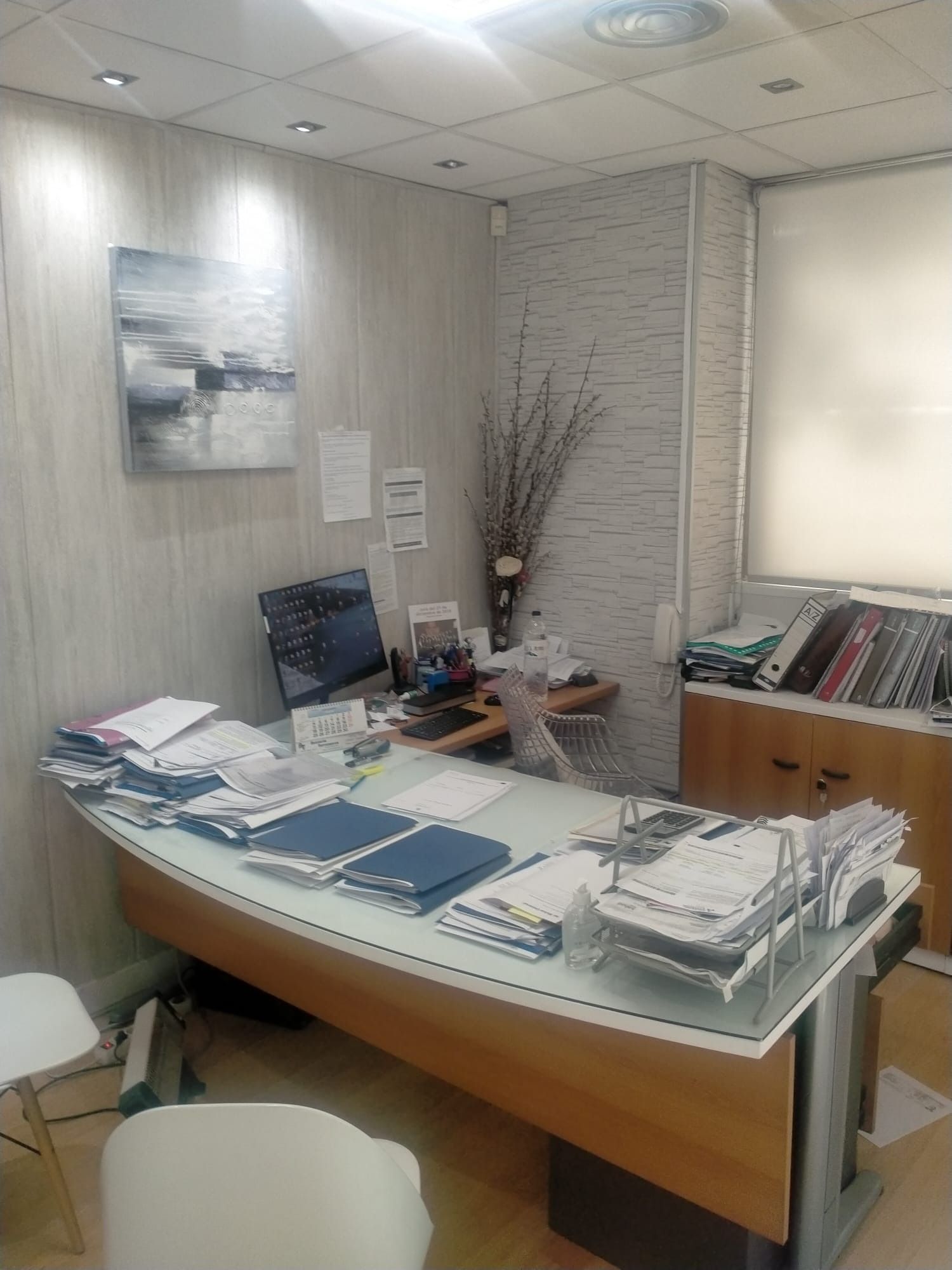 Una habitación con un escritorio y sillas y un cuadro en la pared.