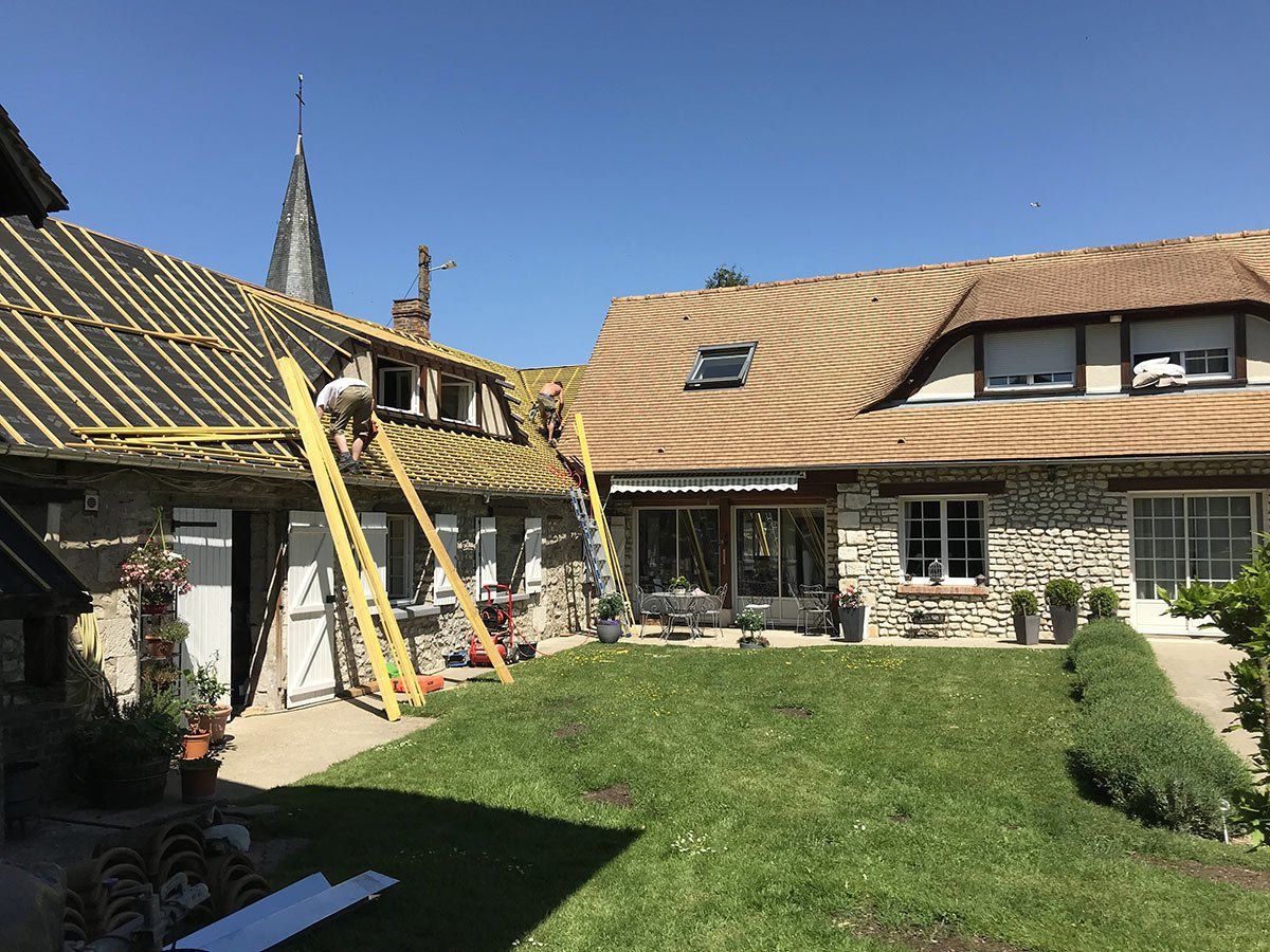 Équipe de MGC qui pose une couverture sur un toit ancien.