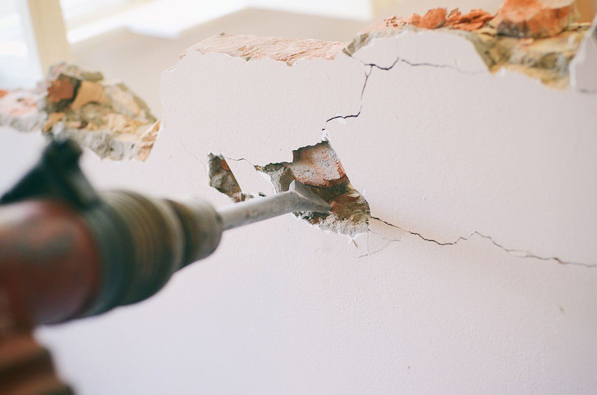 Homme avec une perceuse qui troue un mur.