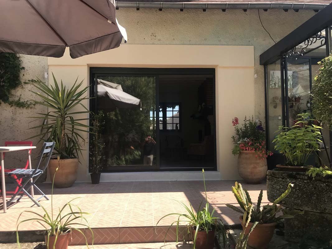 Baie coulissante qui donne sur une terrasse.