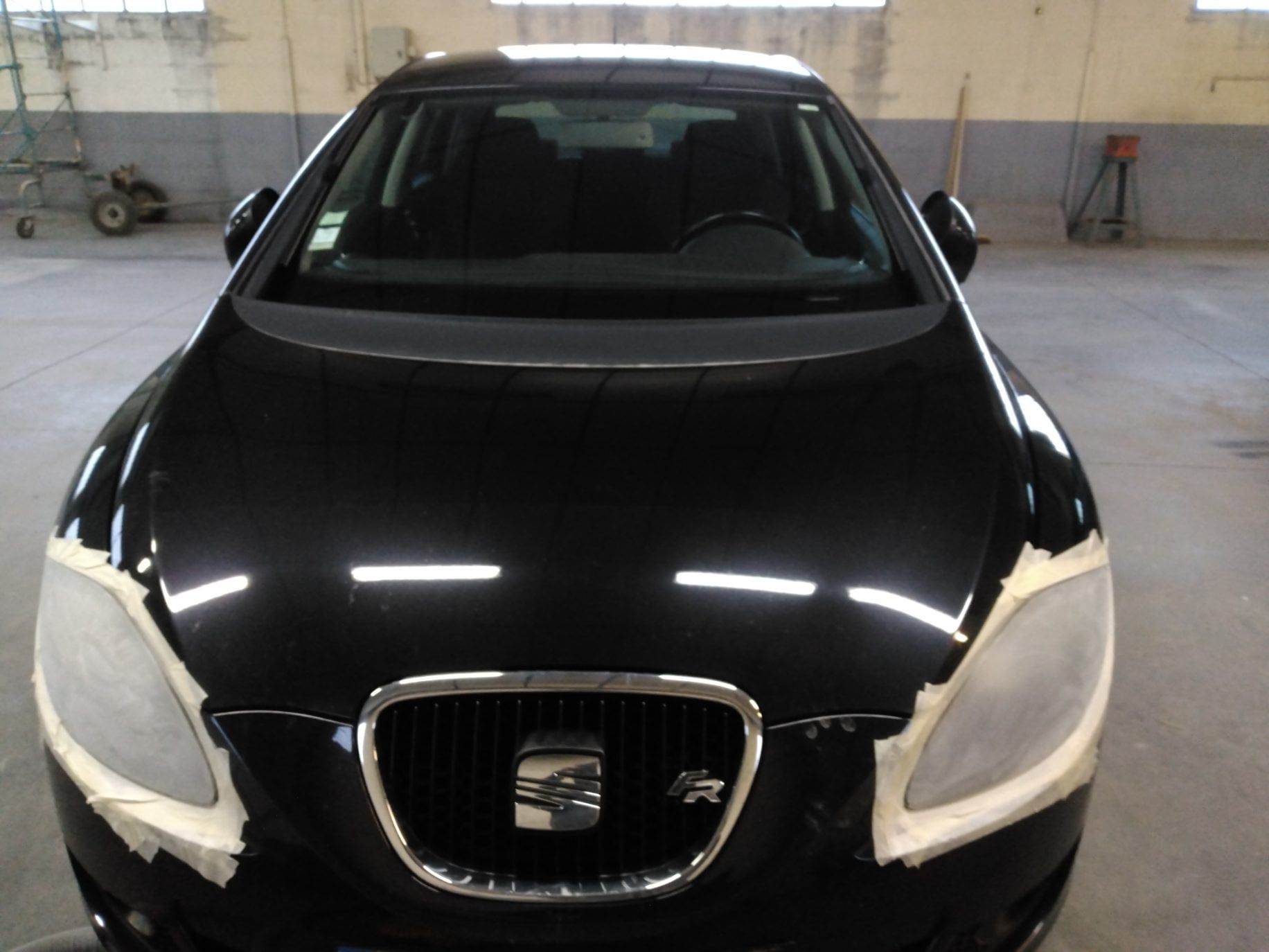 Travaux en cours pour nettoyer les phares d'une Seat noire