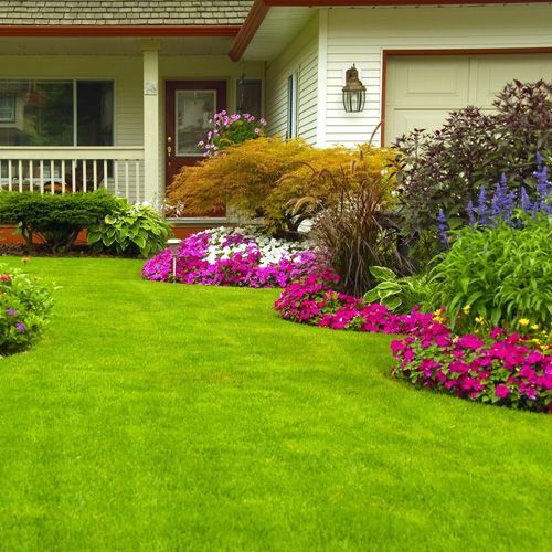 Una casa con un exuberante césped verde y flores en el frente.