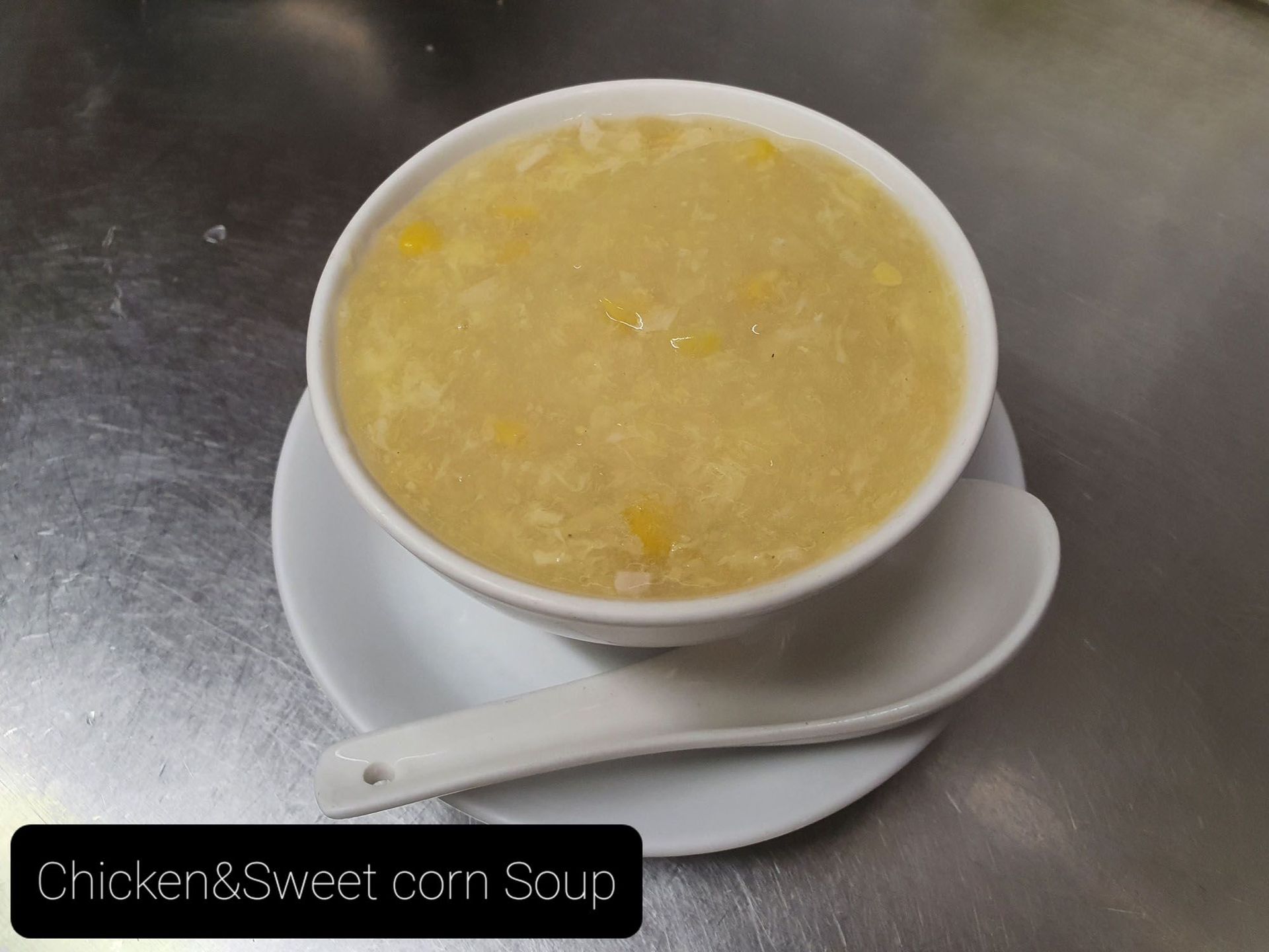 Eine Schüssel Hühner- und Maissuppe mit einem Löffel