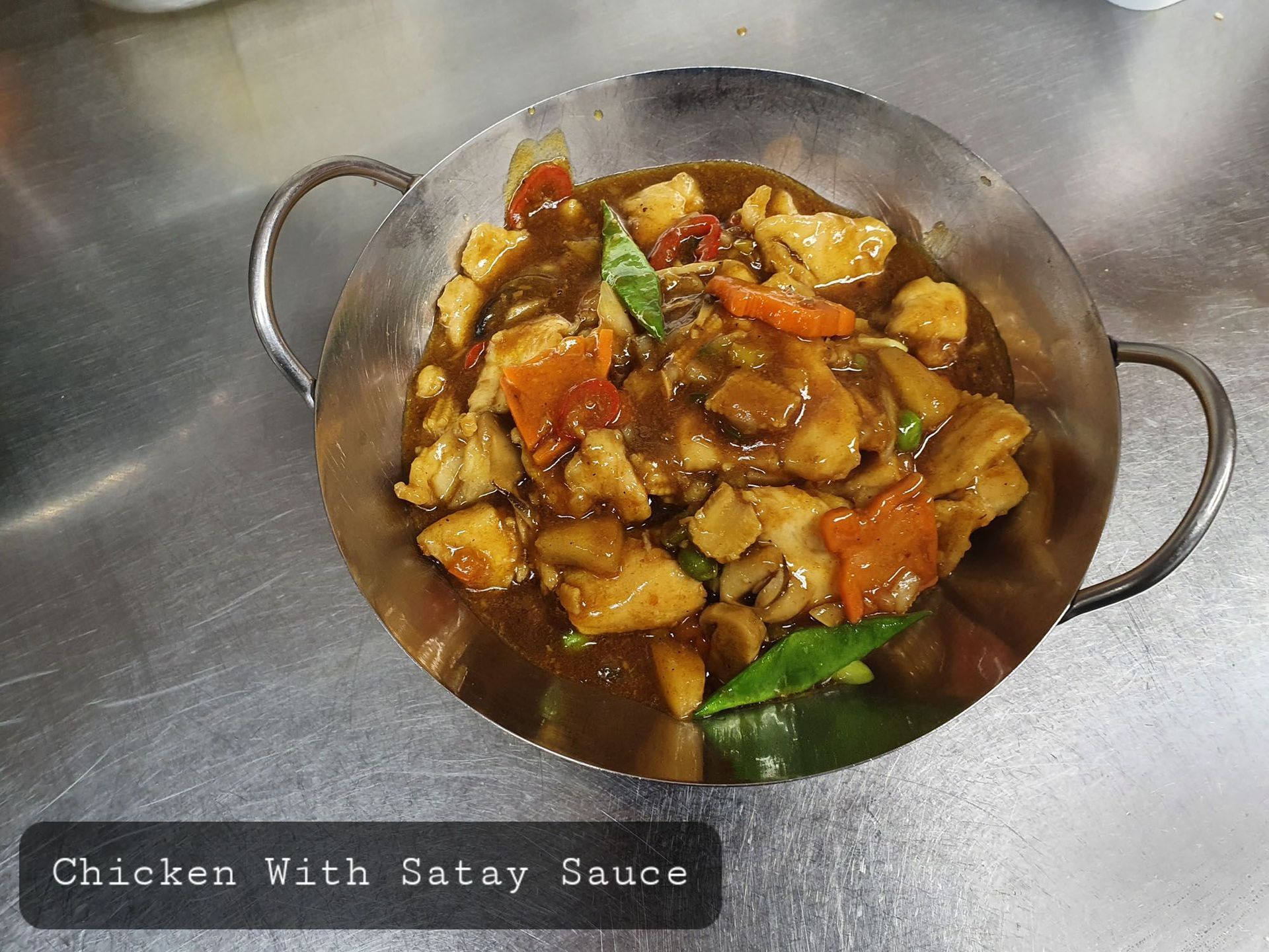 Eine Schüssel Hühnchen mit Saté-Sauce auf einem Tisch.