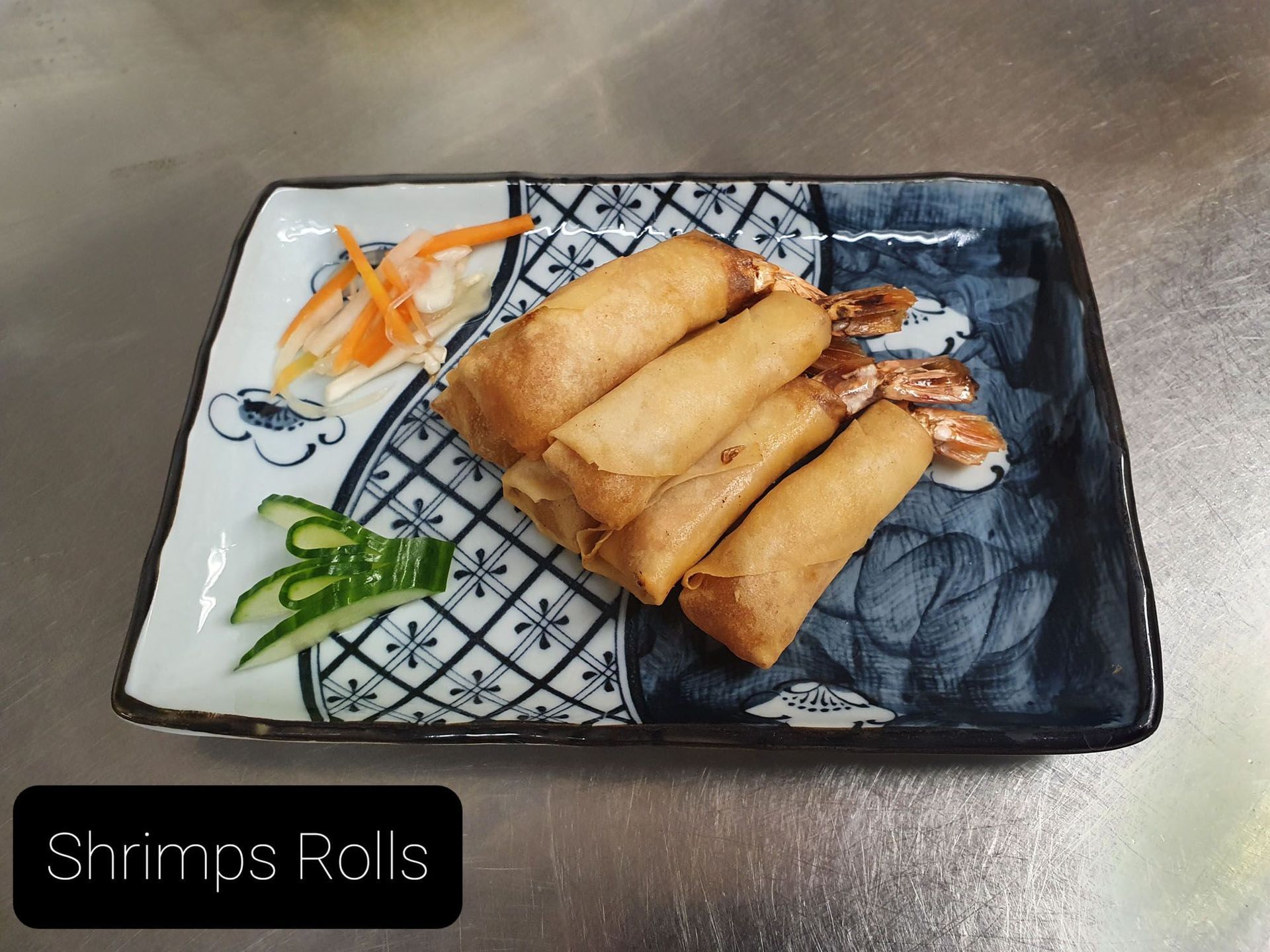 Ein Teller mit Garnelenröllchen und Gemüse auf einem Tisch.