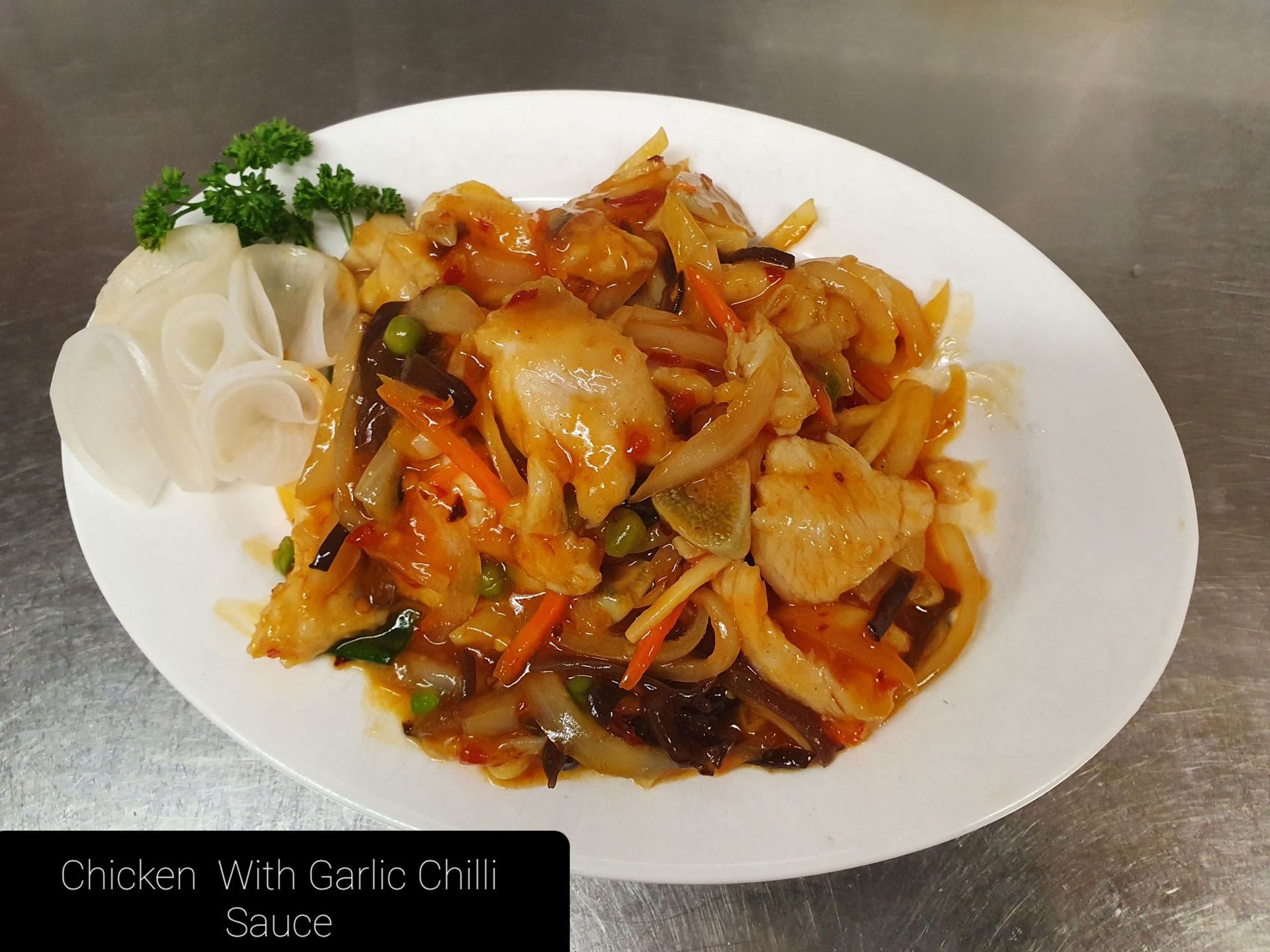 Ein weißer Teller mit Hühnchen und Knoblauch-Chili-Sauce