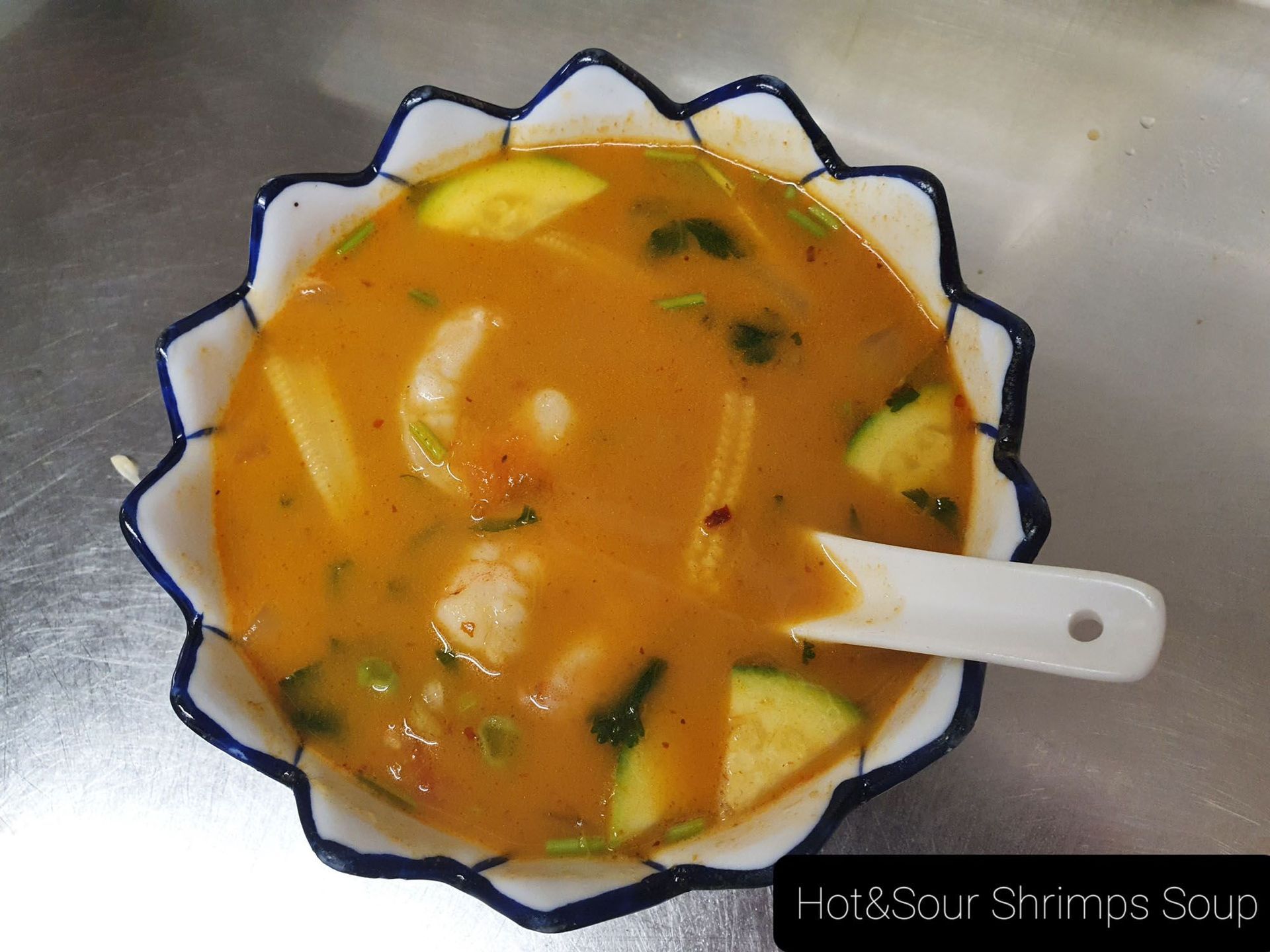 Eine Schüssel scharf-saure Garnelensuppe mit einem Löffel darin