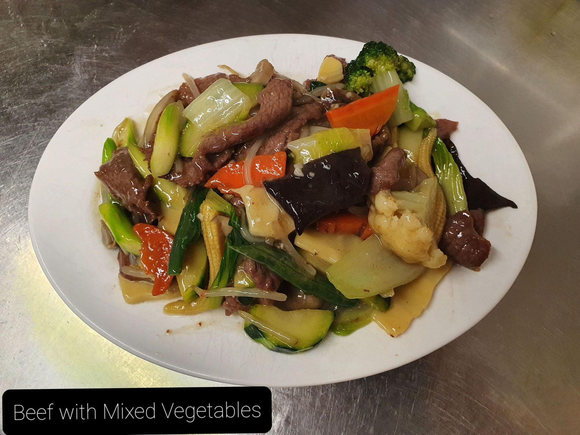 Ein weißer Teller mit Rindfleisch und gemischtem Gemüse