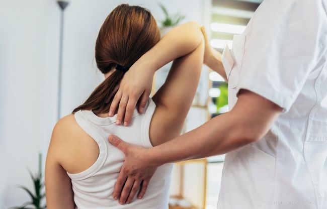 Ein Arzt untersucht die Rückenschmerzen eines Patienten in einer Klinik.